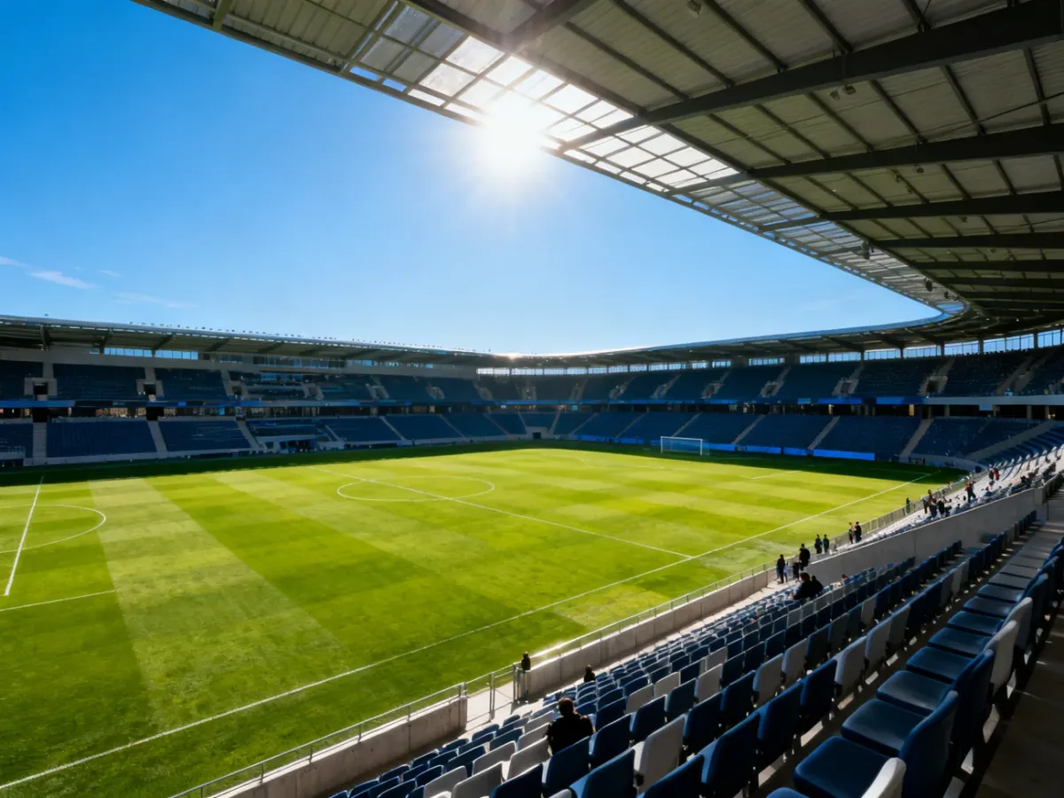 Boisko piłkarskie oświetlone słońcem pod częściowym dachem stadionu