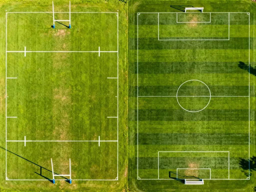 Porównanie boiska do rugby z bramkami w kształcie litery H oraz boiska piłkarskiego z prostokątnymi bramkami.